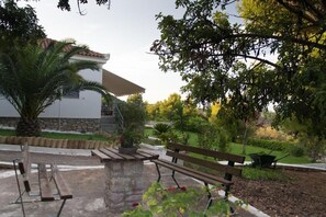 Um pátio com bancos, uma palmeira e um edifício com base de pedra e telhado em azulejos.
