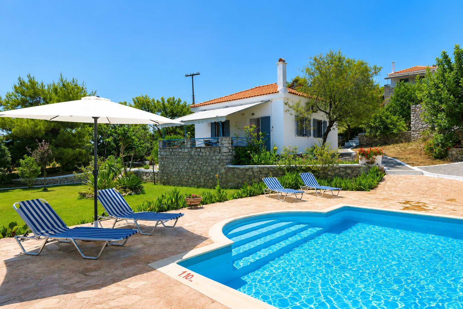 A swimming pool with lounge chairs and a stone wall.
