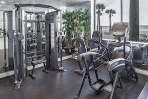 Een fitnessruimte met Cybex apparatuur, een loopband en uitzicht op de oceaan.