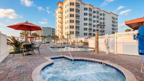 Ein Hotelpoolbereich mit Whirlpool, Liegestühlen und Sonnenschirmen.
