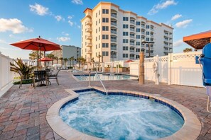 Un espace piscine d’hôtel comprenant un jacuzzi, des chaises longues et des parasols.