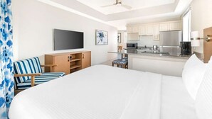 Ein Hotelzimmer mit einem Bett, einem Fernseher, einer Küchenzeile und einem Deckenventilator.