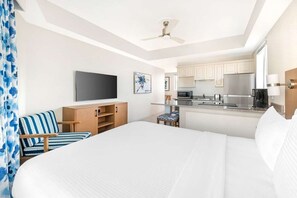 Une chambre d’hôtel équipée d’un lit, d’une télévision, d’une kitchenette et d’un ventilateur de plafond.