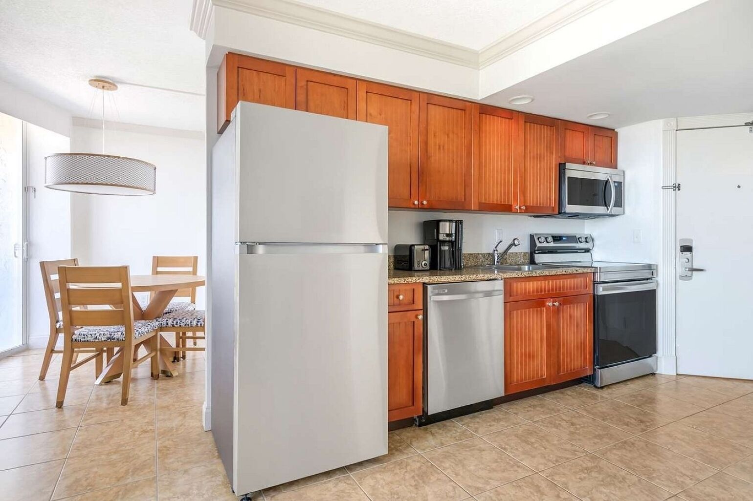 A modern kitchen with wooden cabinets, stainless steel appliances, and a dining area with a table and chairs.