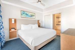 A hotel room with a large bed, a ceiling fan, a painting, a nightstand, and a bathroom visible through an open door. - Ormond Beach | Beach Escape | Pool & Ocean Access | 2BR Lockoff (Ormond Beach)