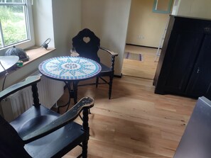 A room with a round table, a chair, a radiator, a window, and a door. - "Knight’s Room" in Farmhouse on Riding Estate (Malente)