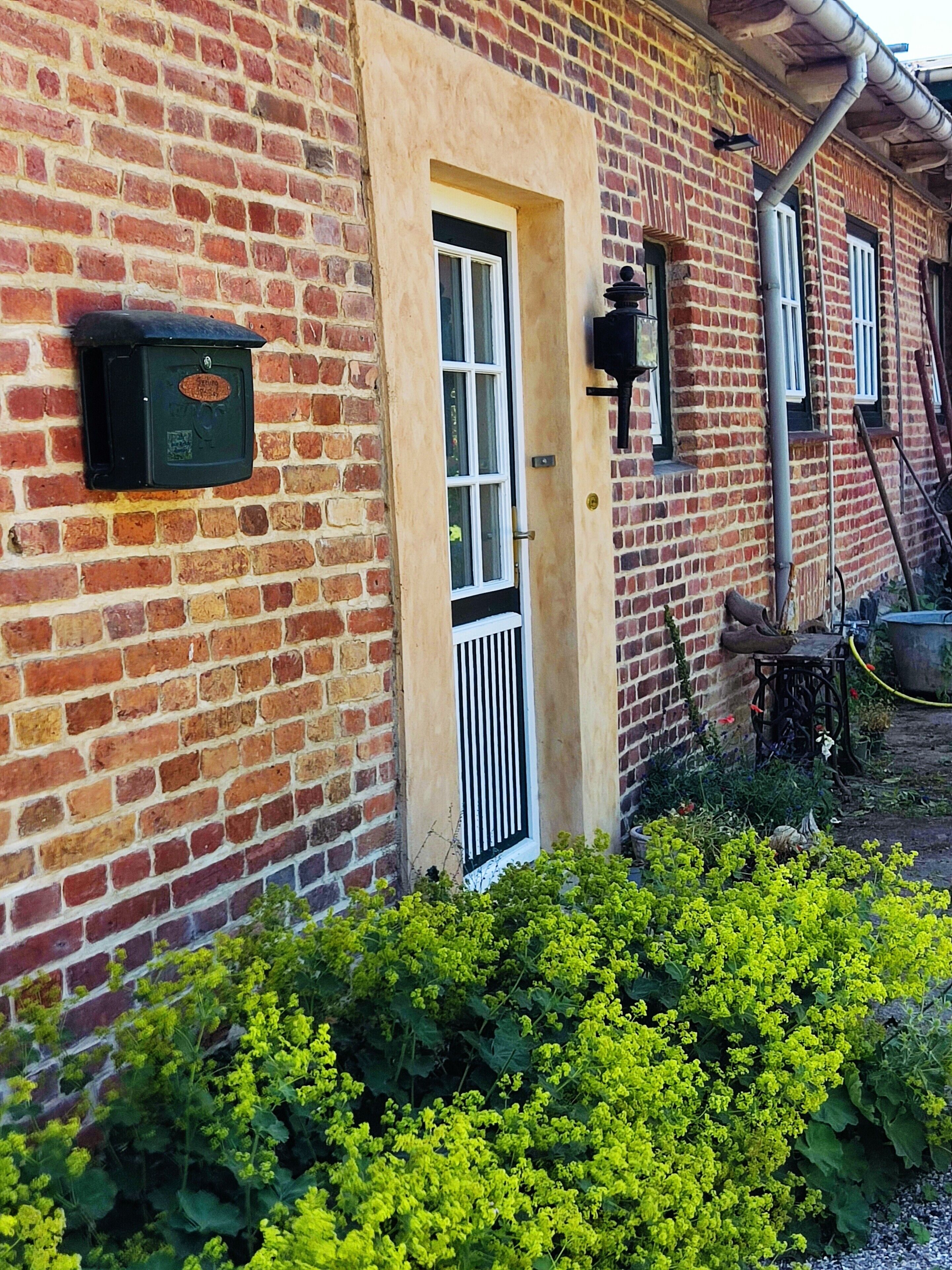 Ein Backsteinhaus mit Tür, Briefkasten und Fenster.