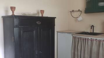 Eine kleine Küche mit einem dunklen Holzkorpus, einem Kühlschrank und einem Waschbecken mit einem grünen Schrank darüber.