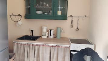 Eine kompakte Küchenzeile mit Spüle, Kaffeemaschine, Wasserkocher und Herd.