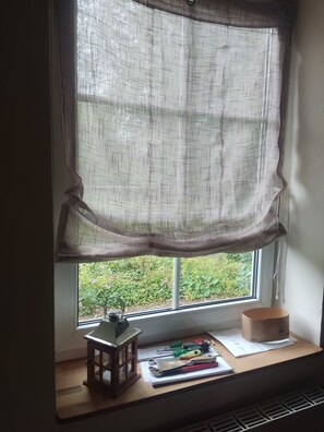 A window with a sheer curtain, a small wooden lantern, and various tools on a ledge.