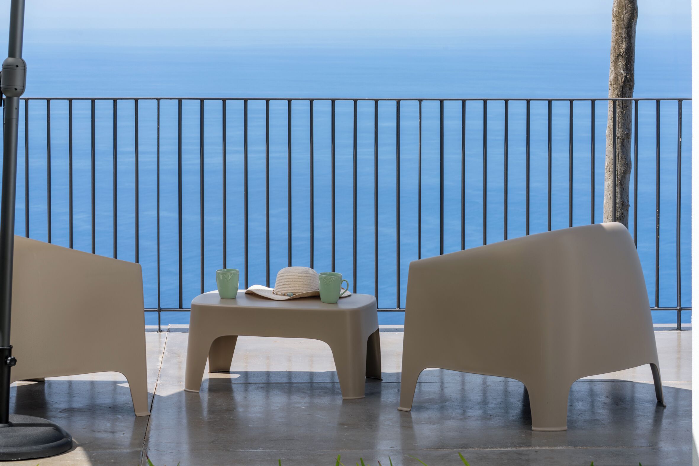 A balcony with two chairs and a small table, overlooking a body of water.