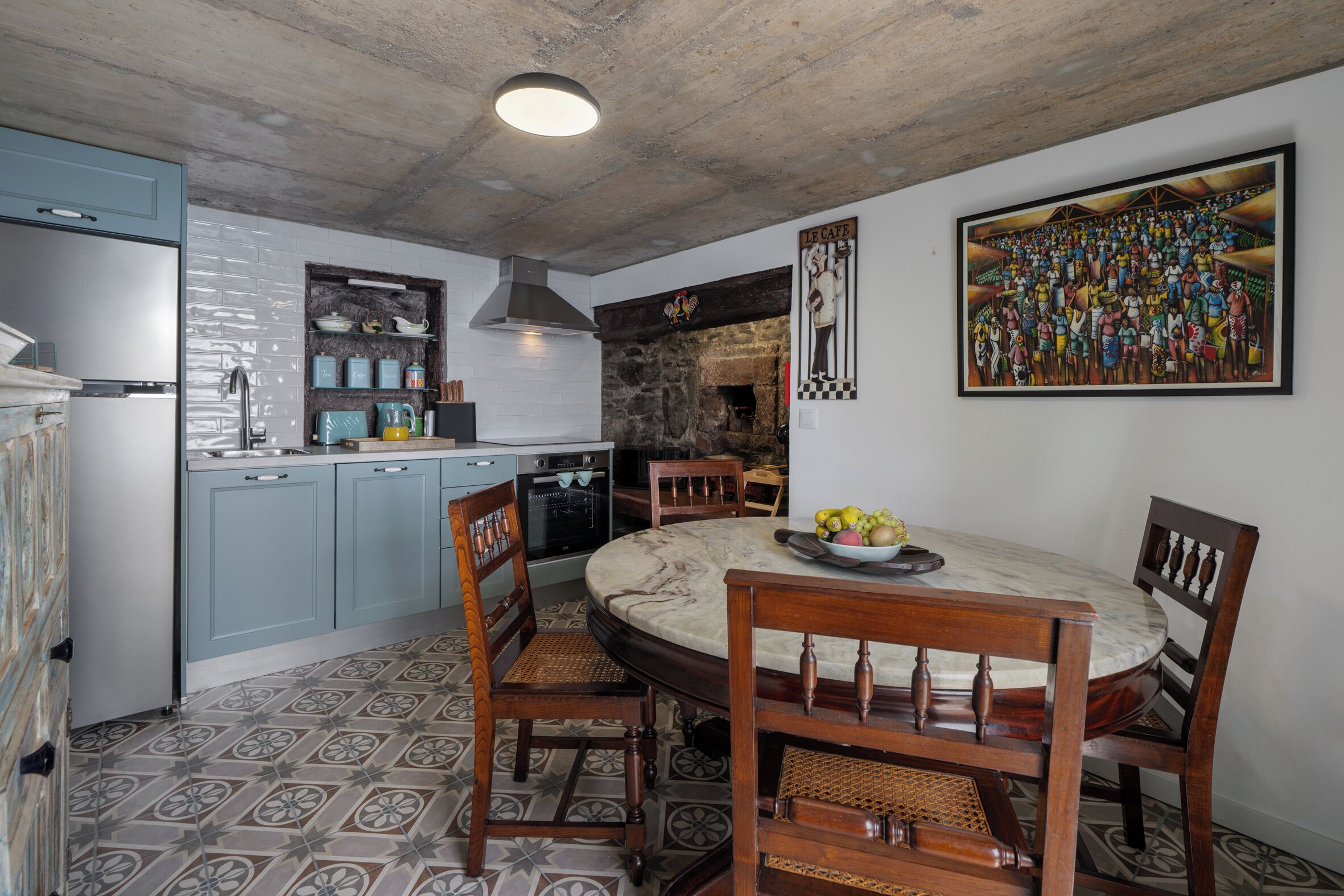 Une cuisine avec un mur en pierre, une table de salle à manger ronde entourée de chaises et une fresque murale.