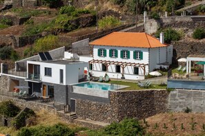 Ein modernes Haus mit Swimmingpool, Steinmauern und Garten.