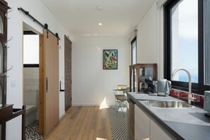 A modern kitchen with a large window, a sink, and a coffee maker. - Tranquil with seaview|Ocean Hills Garden Studio (Faja Da Ovelha)