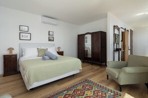 A bedroom with a bed, a wardrobe, a chair, and a rug. - Tranquil with seaview|Ocean Hills Garden Studio (Faja Da Ovelha)