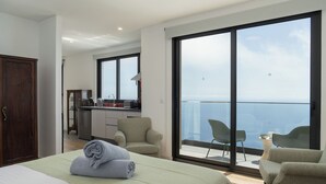 Ein Hotelzimmer mit Bett, Schreibtisch, Stuhl, einem Balkon mit Aussicht und einem Kleiderschrank.