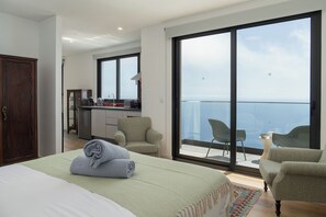 Ein Hotelzimmer mit Bett, Schreibtisch, Stuhl, einem Balkon mit Aussicht und einem Kleiderschrank.