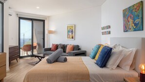 Une chambre moderne avec un grand lit, un canapé, un bureau et un balcon.