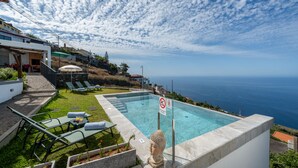 Une piscine avec vue sur l’océan, une statue de Bouddha et un panneau indiquant qu’il est interdit de se baigner.