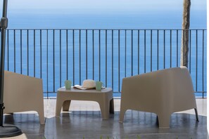 A balcony with two chairs and a small table, overlooking a body of water. - Tranquil with seaview|Ocean Hills Terrace Studio (Faja Da Ovelha)