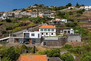 A hillside residential area with modern houses, a swimming pool, and a view of the sea. - Tranquil with seaview|Ocean Hills Terrace Studio (Faja Da Ovelha)