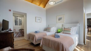 Une chambre d’hôtel avec deux lits, un bureau, une chaise et un téléviseur.