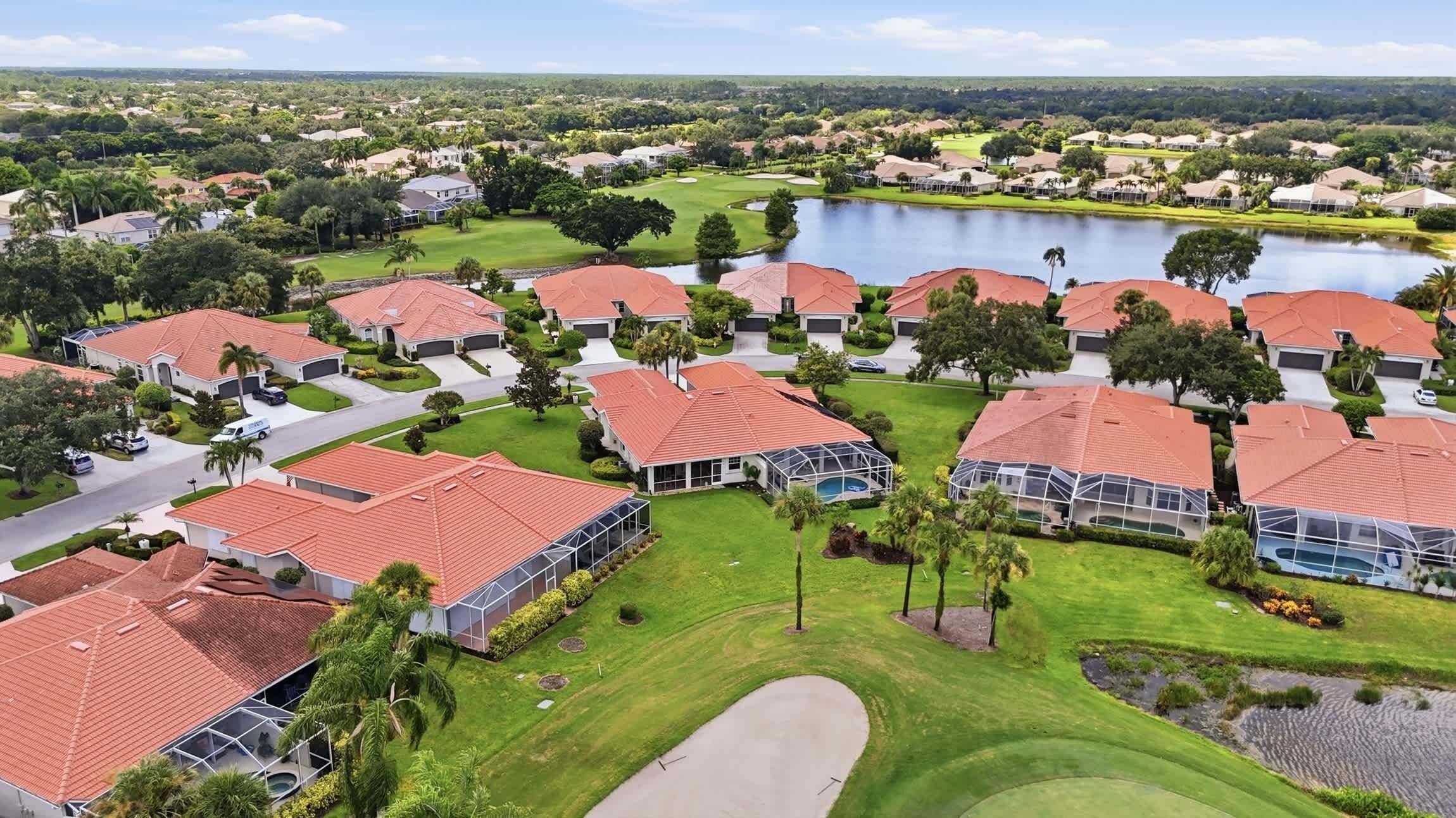 A residential area with houses, a golf course, and a lake.