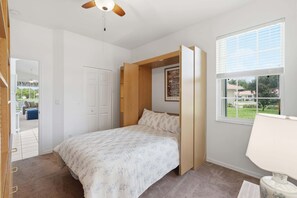 A bedroom with a bed, a window, a ceiling fan, and a door. - Villa With Lake and Golf Views on Public Arrowhead Golf Course (Naples)
