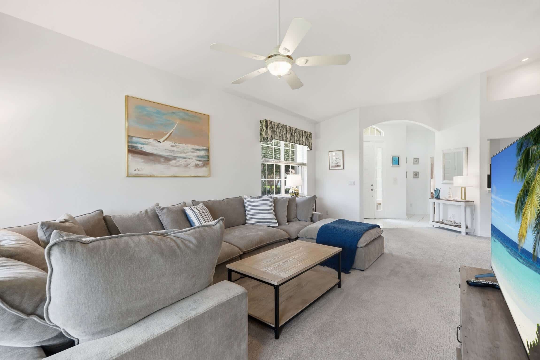 A modern living room with a sectional sofa, a coffee table, and a flat-screen TV.