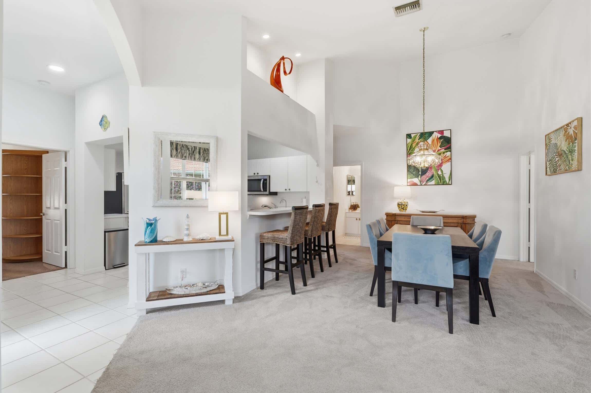 A spacious living area with a dining table, chairs, a kitchen, and a hallway.
