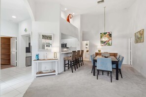 A spacious living area with a dining table, chairs, a kitchen, and a hallway.