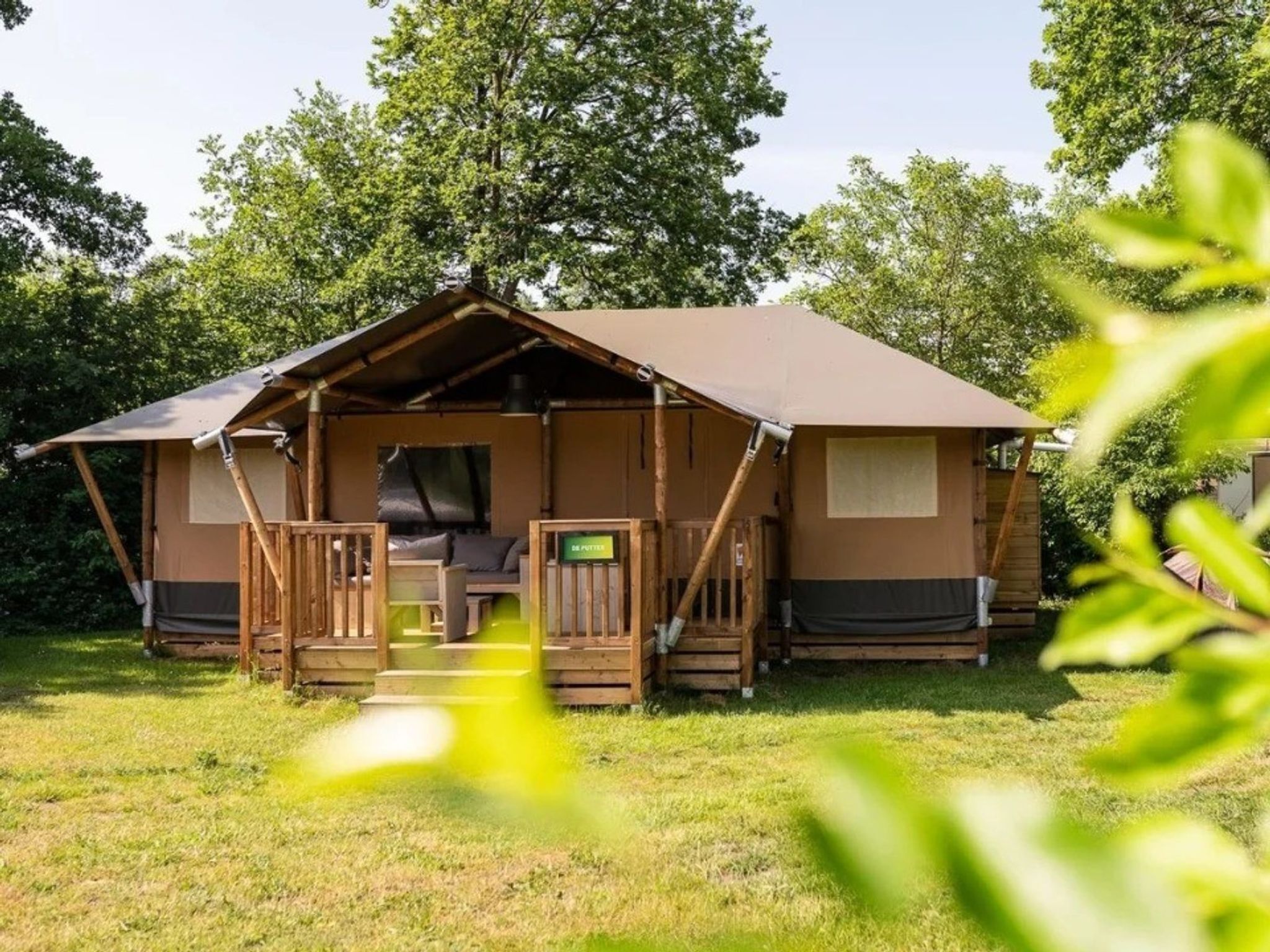 Eine einstöckige Holzhütte mit Veranda, einer kleinen Sitzecke und einem Schild, das ein Badezimmer anzeigt.