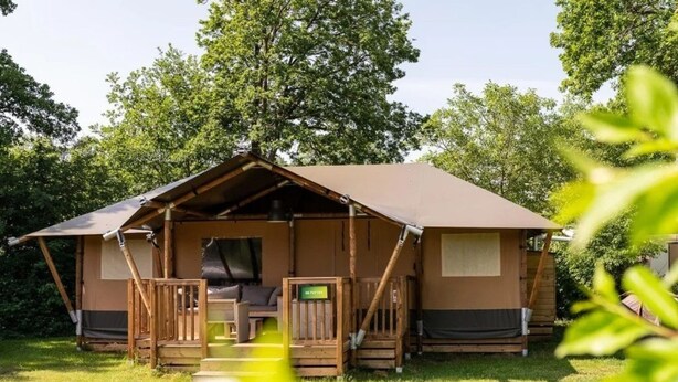 A single-story wooden cabin with a porch, a small seating area, and a sign indicating a bathroom. - Wilsumer Berge Resort - Glamfield Lodge 8 by Interhome (Wilsum)