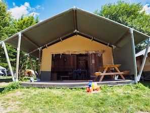 Una carpa con un porche cubierto, bancos de madera y una mesa de picnic.