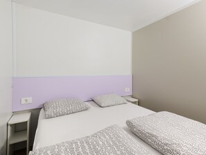 A bedroom with a bed, two bedside tables, and a headboard.