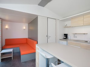 Una kitchenette compacta con horno integrado, una pequeña encimera y cafetera.