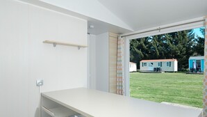 A modern room with a white desk, two chairs, a window with curtains, and a view of mobile homes. - Vacation home by Interhome (Osecná)