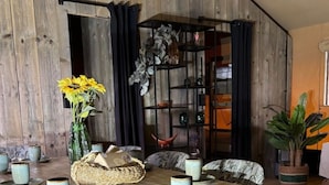 A dining area with a wooden table, floral upholstered chairs, and a decorative vase with sunflowers. - Wilsumer Berge Resort - Glamfield Lodge Premium by Interhome (Wilsum)