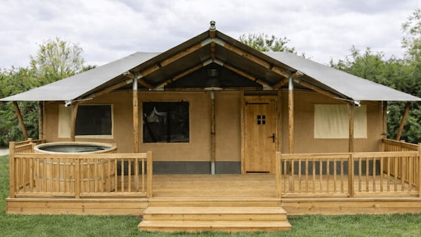A wooden cabin with a pitched roof, a front porch, and a hot tub. - Wilsumer Berge Resort - Glamfield Lodge Premium by Interhome (Wilsum)