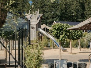 Un terrain de jeux avec un toboggan, une structure d’escalade et une tente.