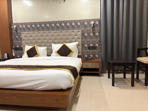 A hotel room with a bed, bedside tables, a chair, and a decorative wall. - HOTEL PALASH (Danapur)