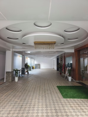 Amplio espacio interior con piso estampado, un candelabro central y plantas en macetas.