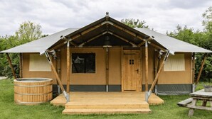 Een houten blokhut met een schilddak, een houten deur en een klein terras.