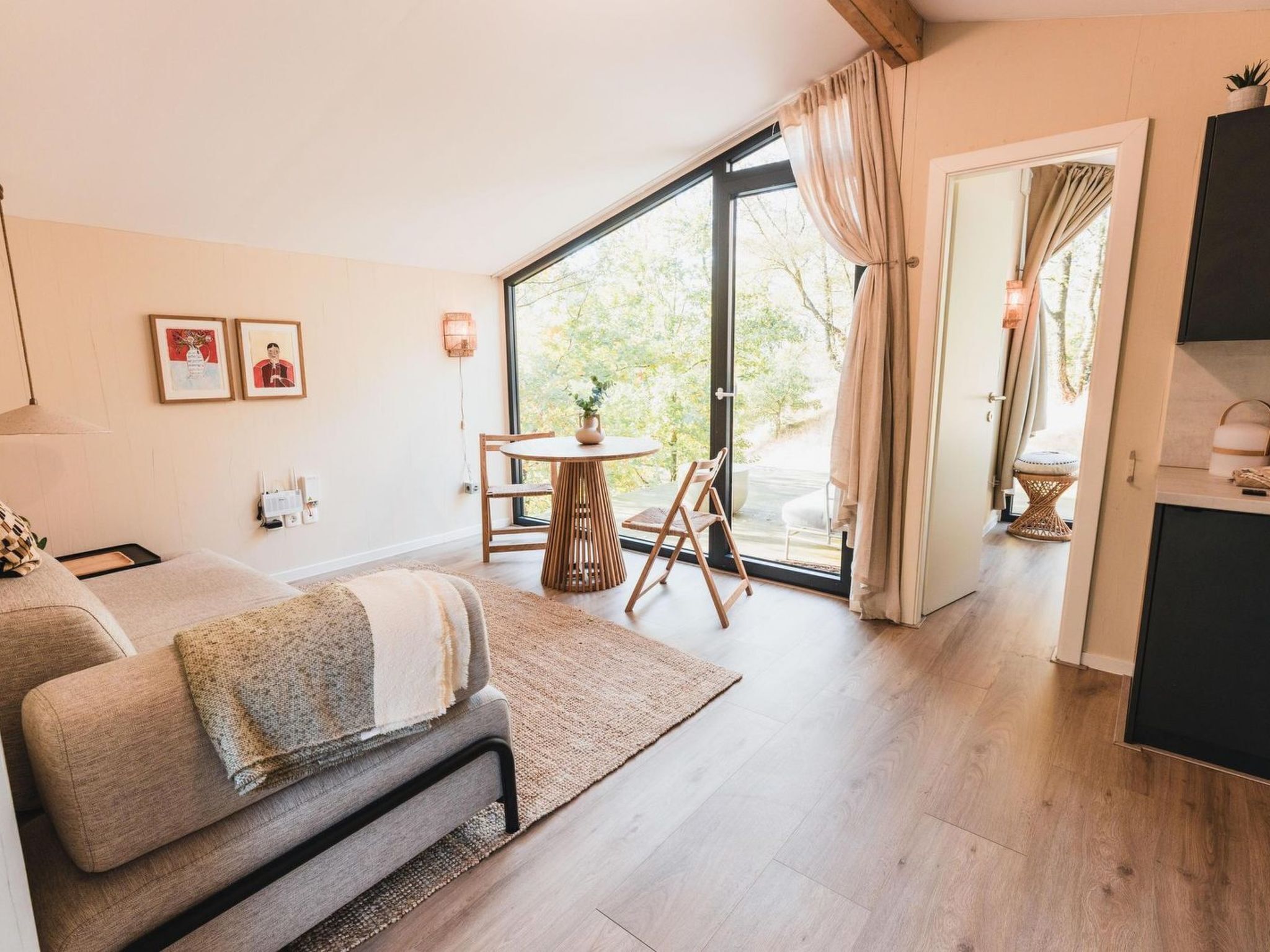 Ein modernes Zimmer mit einer Couch, einem kleinen Tisch mit Pflanze und Blick durch eine Glastür.