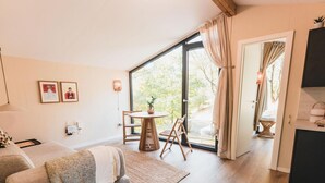 Ein modernes Zimmer mit einer Couch, einem kleinen Tisch mit Pflanze und Blick durch eine Glastür.