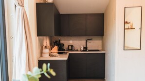 Eine kleine Küche mit dunklen Schränken, einer kompakten Arbeitsfläche und Holzboden.