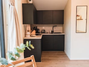 A compact kitchen with dark cabinets, a small countertop, and a wooden floor. - Wilsumer Berge Resort - Cabin on the Hill by Interhome (Wilsum)