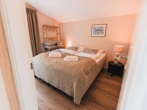 A neatly made bed with pillows and a blanket, a bedside table with a lamp, and a wooden ladder against the wall. - Wilsumer Berge Resort - Cabin on the Hill by Interhome (Wilsum)