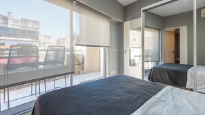 Et moderne hotelværelse med balkon, seng, stol og stort vindue.