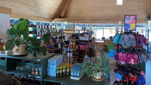 A store with wooden ceiling and shelves stocked with various items including jars, bottles, and children's shoes. - Wilsumer Berge Resort - Trekkershut by Interhome (Wilsum)